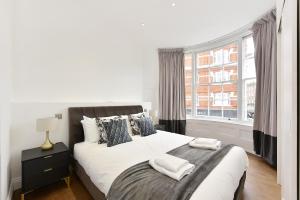 1 dormitorio con 1 cama con 2 toallas en London Choice Apartments - Chelsea - Sloane Square en Londres