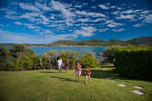 a family walking on the grass near a lake at Hotel Palumbalza Porto Rotondo in Porto Rotondo