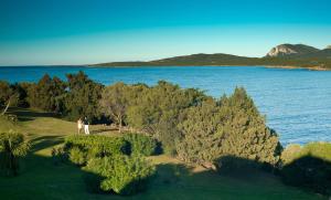 two people standing on a hill near a body of water at Hotel Palumbalza Porto Rotondo in Porto Rotondo