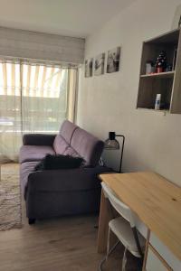 salon z fioletową kanapą i stołem w obiekcie Studio Andernos vue Bassin port ostréicole charmant et lumineux avec piscine et balcon ! w mieście Andernos-les-Bains