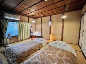 - une chambre avec 2 lits et une fenêtre dans l'établissement Guesthouse Naramachi, à Nara