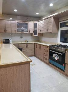 a kitchen with wooden cabinets and a stove at فلل فندقية بمدينة تنومة in Ithnayn