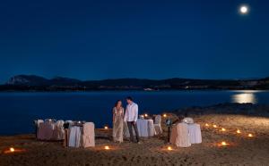 a bride and groom standing on the beach at night at Hotel Palumbalza Porto Rotondo in Porto Rotondo