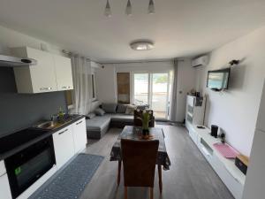 a kitchen and living room with a table and a couch at Apartmani Premijer-Rab in Supetarska Draga