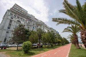a large building with palm trees in front of it at Amazing Magnolia in Batumi