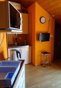 uma cozinha com paredes cor de laranja e um relógio na parede em Apartman Crikvenica 30099 - Dane em Crikvenica
