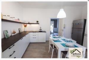a kitchen with a white table and a black refrigerator at Gelkamar Apartment in Santa Flavia