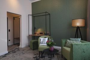 a living room with green chairs and a mirror at LIHO - einfach Lübeck in Lübeck