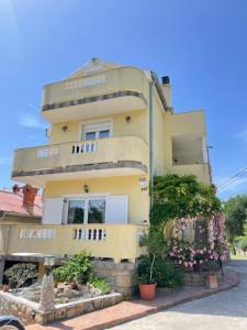 wysoki żółty budynek z roślinami przed nim w obiekcie apartment IVA w mieście Supetarska Draga