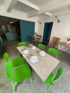 Zimmer mit einem Tisch und grünen Stühlen in der Unterkunft Qiwi House in Ureki