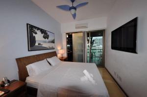een slaapkamer met een wit bed en een televisie bij IPF2045C - Tiffany's Residence Service - Ipanema in Rio de Janeiro
