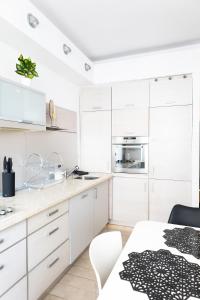 a white kitchen with white cabinets and a table at ClickTheFlat Szkolna Palace of Culture Apart Rooms in Warsaw
