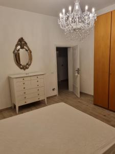 um quarto com um lustre, uma cómoda e um espelho em Appartamento Via Loreto em Pistoia