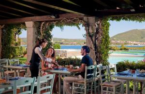 a group of people sitting at tables at a restaurant at Hotel Palumbalza Porto Rotondo in Porto Rotondo
