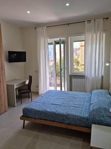 a bedroom with a blue bed and a desk and window at Casa Sofia in Gaeta