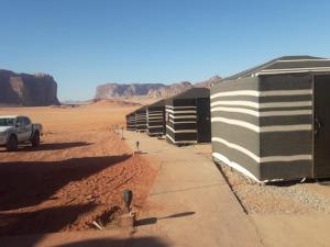 a truck parked next to a row of buildings in the desert at WadiRum Mobile Camp in Wadi Rum