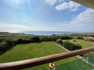 a view from a balcony of a yard with the ocean at Sea View 5 Bed House Next To Water Sports & Golf in Porthcawl