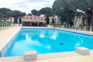 una grande piscina blu con alberi sullo sfondo di Nuria Superbe Meublé 3* avec loggias 250m des plage a Plage dʼArgelès