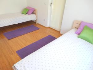Duas camas num quarto com almofadas roxas e verdes em Apartman Crikvenica 30103 - Zdravko em Crikvenica