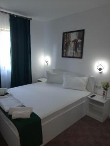 sypialnia z dużym białym łóżkiem i oknem w obiekcie Casa Chriss w mieście Eforie Sud