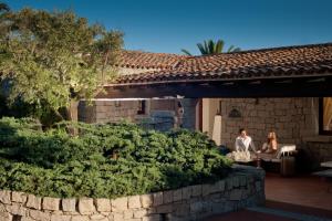 a man and woman sitting on the porch of a house at Hotel Palumbalza Porto Rotondo in Porto Rotondo