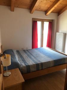 um quarto com uma cama e uma janela com cortinas vermelhas em Casa dell'Olivo em Castione Andevenno
