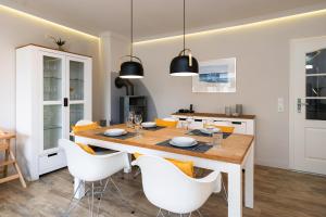 ein Esszimmer mit einem Holztisch und weißen Stühlen in der Unterkunft Süderliebe in Westerland