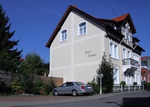 ein Auto, das vor einem weißen Gebäude parkt in der Unterkunft Hotel Galerie in Seelze