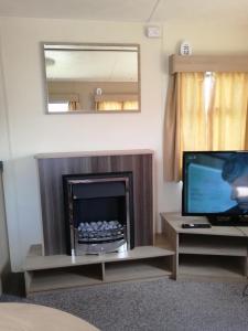 un salon avec une cheminée et une télévision dans l'établissement YY20 Martello Beach Holiday Park, à Clacton-on-Sea