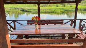 una mesa de madera con un jarrón de flores sentado en un porche en Sodyba pas Juozą, en Milkai