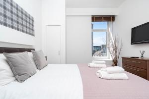 a white bedroom with a large bed with towels on it at Howburn Residence Serviced Apartments - 1,2& 3 Bedroom Apartments in Aberdeen