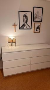 - une commode blanche dans une pièce avec une croix sur le mur dans l'établissement Apartment near Europa-Park & Black Forest, à Kappel-Grafenhausen