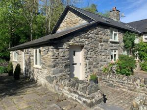 an old stone house with a white door at Stable Cottage in Corwen