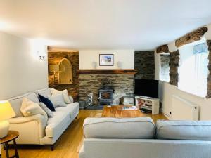 a living room with two couches and a stone fireplace at Stable Cottage in Corwen