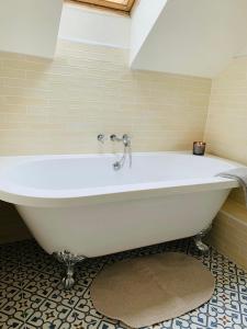 La salle de bains est pourvue d'une baignoire blanche et de carrelage. dans l'établissement Stable Cottage, à Corwen