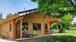 Cabaña de madera pequeña con sillas y porche en Ökologisches Holzblock-Ferienhaus 150 im Lauterdörfle zu vermieten - Neubau, en Hayingen