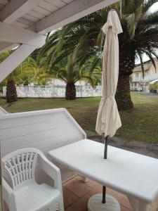 una mesa blanca, un paraguas blanco y un banco en Petit oasis avec piscine en Anglet