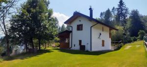 a small white church with a cross on a grass field at Baita Bocheto Vetriolo Levico Terme in Vetriola