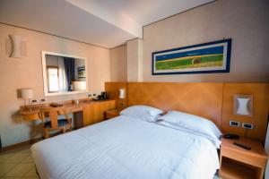 1 dormitorio con 1 cama blanca grande y escritorio en Hotel Centrale, en Bolonia