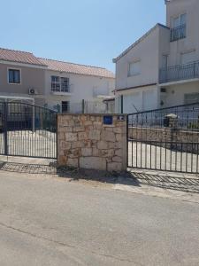 uma cerca de pedra ao lado de um edifício com casas em Apartmani Tamaris em Murter