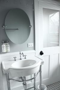 lavabo blanco en el baño con espejo en The Plainfield Inn, en Plainfield