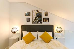 a bedroom with a bed with two yellow pillows at Coutinho Apartment - Modern Ap in the City Centre with Balcony in Viana do Castelo