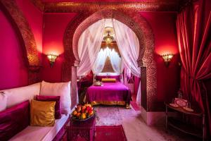 een paarse kamer met een bed en een raam bij Riad Dar El Malaika in El Jadida