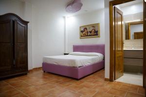 a bedroom with a purple bed and a mirror at Agriturismo I Fornari in Stella Cilento