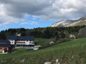 a house in a field with mountains in the background at La Tintaine- T2 avec Terrasse in Villard-de-Lans