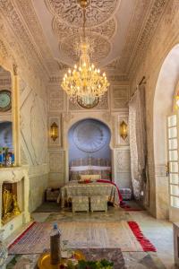 Großes Zimmer mit einem Bett und einem Kronleuchter in der Unterkunft Riad Dar El Malaika in El Jadida