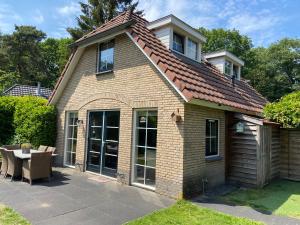 a small brick house with a table in a yard at Bosboerderij de Veluwe, luxe huisje in het bos in Lunteren