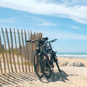 Una bicicleta estacionada junto a una valla en la playa en Soulac-Sur-Mer avec Piscine, en Soulac-sur-Mer