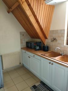 a kitchen with white cabinets and a sink at Haras des Buissonnets in Bois-Anzeray