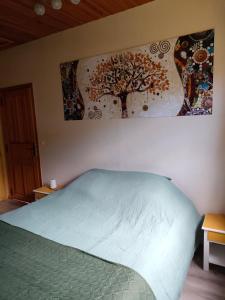 1 dormitorio con 1 cama y una pintura en la pared en Haras des Buissonnets, en Bois-Anzeray